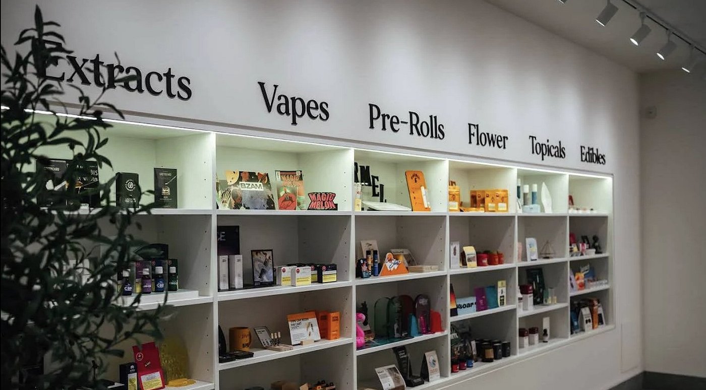 Cancun Dispensary Weed Smokeshop — white gallery shelves under strip lights with serif wall lettering